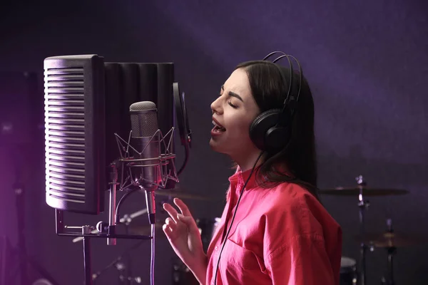 Young singer with microphone recording song in studio — Stock Photo, Image