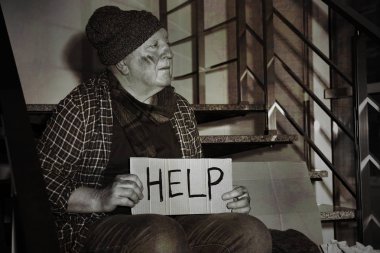 Karton işareti ile zavallı kıdemli adam kapalı merdivenler yardım