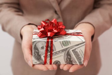 Kadın tutan hediye kutusu ışık arka planda dolar sarılmış, çekim