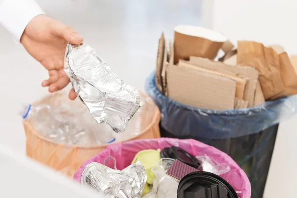 Человек кладет использованную фольгу в мусорный бак, крупным планом. Переработка отходов — стоковое фото