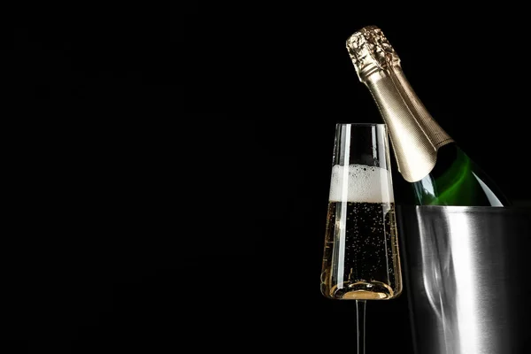 Glass of champagne near bucket with bottle on black background, space for text — Stock Photo, Image