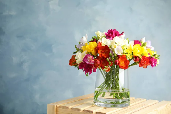 Bukett av våren Freesia blommor i vas på färg bakgrund. Utrymme för text — Stockfoto