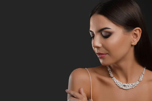 Hermosa mujer joven con joyas elegantes sobre fondo oscuro. Espacio para texto — Foto de Stock