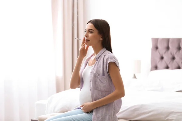 Jovem grávida fumando cigarro em casa — Fotografia de Stock