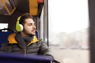 Genç adam toplu taşıma kulaklıklar ile müzik dinleme