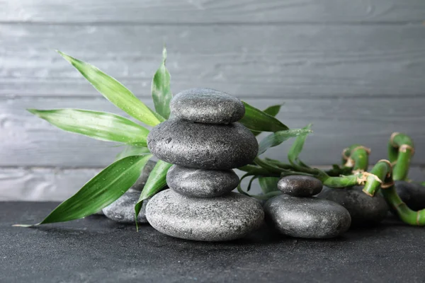 Ułożone kamienie Zen i bambusowe liście na stole z drewnianym tłem — Zdjęcie stockowe