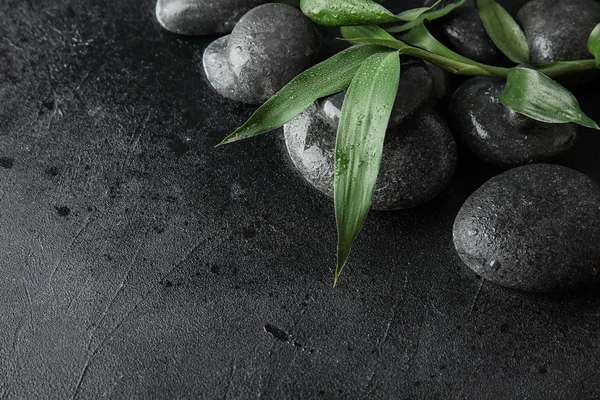 Zen stones and bamboo leaves on black background, closeup. Space for text