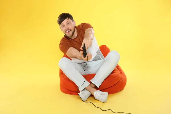 Homme émotionnel jouant à des jeux vidéo avec contrôleur sur fond de couleur — Photo