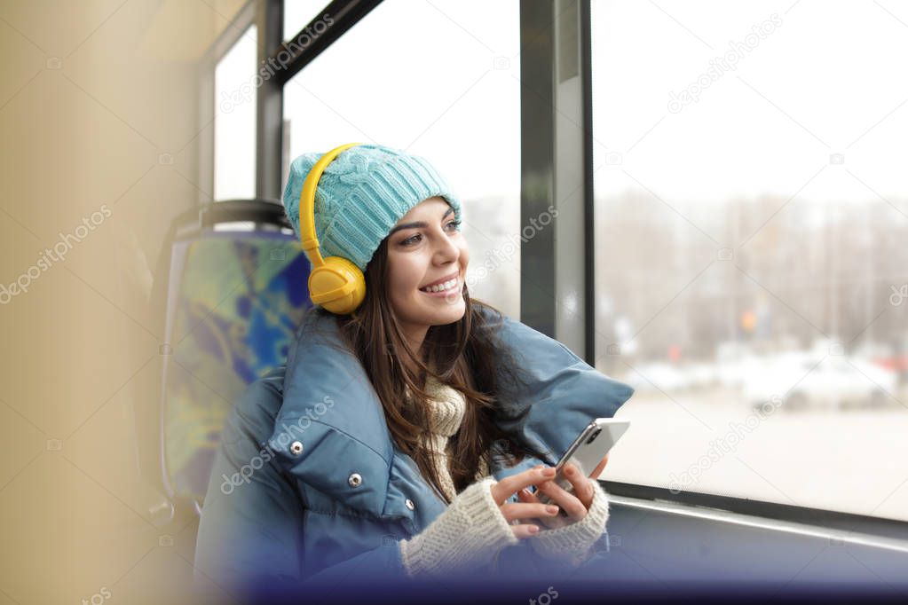 Young woman listening to music with headphones in public transport