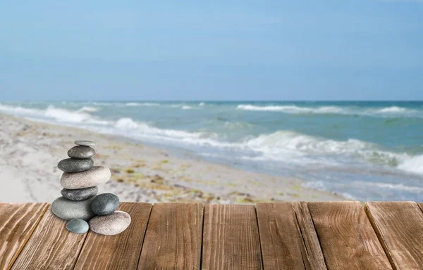 Stacked zen stones on wooden pier against seascape, space for text