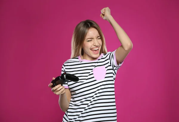 Συναισθηματική νεαρή γυναίκα παίζοντας βιντεοπαιχνίδια με χειριστήριο στο φόντο χρώμα — Φωτογραφία Αρχείου