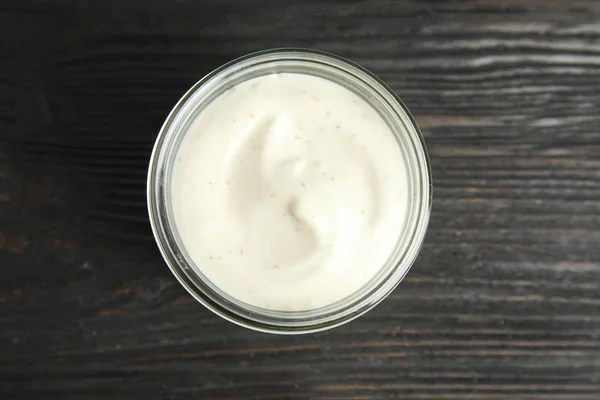 Jar of garlic sauce on wooden background, top view — Stock Photo, Image