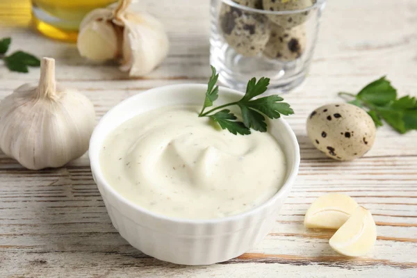 Samenstelling met kom knoflooksaus op houten tafel — Stockfoto