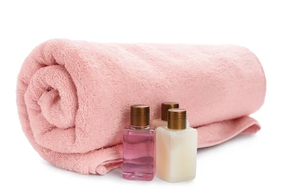 Mini bottles with cosmetic products and towel on white background. Hotel amenities