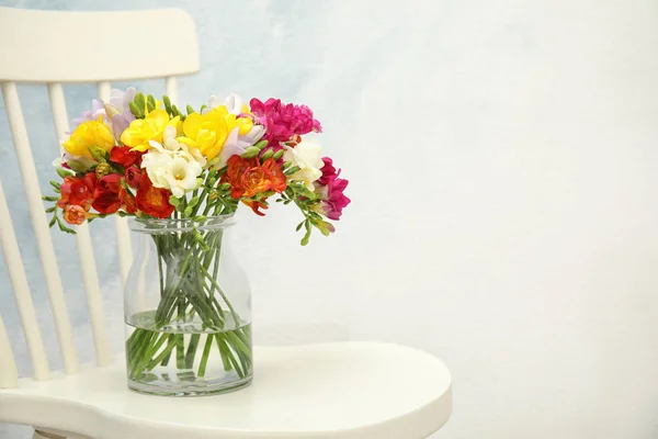 Beautiful spring freesia flowers in vase on chair. Space for text — Stock Photo, Image