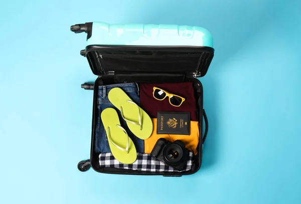 Valigia aperta con effetti personali del viaggiatore su sfondo a colori, vista dall'alto — Foto Stock