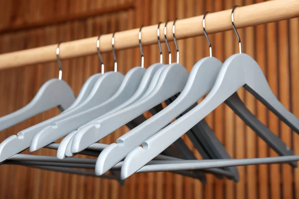 Empty hangers on rail against wooden background — Stock Photo, Image