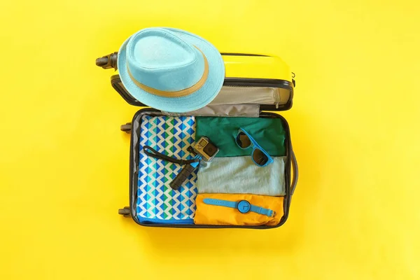 Open suitcase with summer clothes and accessories on color background, top view — Stock Photo, Image