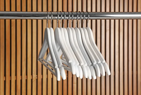 Empty hangers on rail against wooden background — Stock Photo, Image