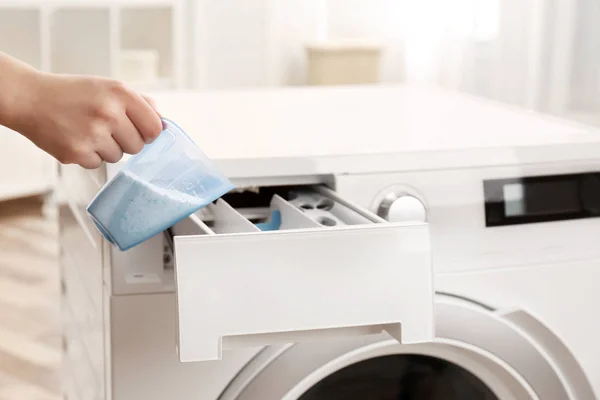 Kadın iç mekanlarda çamaşır makinesinin çekmecesine toz akıtıyor. Çamaşırhane günü — Stok fotoğraf