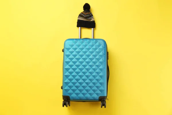 Стильный чемодан с теплой шляпой на цветном фоне, вид сверху — стоковое фото