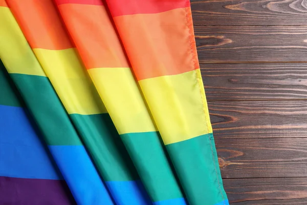 Bandera gay arco iris brillante sobre fondo de madera, vista superior con espacio para el texto. Comunidad LGBT —  Fotos de Stock