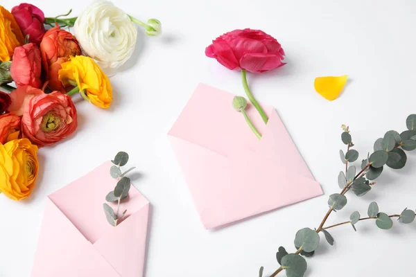 Komposition med vackra Ranunculus blommor och kuvert på vit bakgrund — Stockfoto