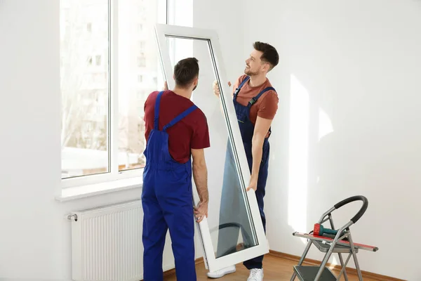 Construction workers installing plastic window in house — Stock Photo, Image