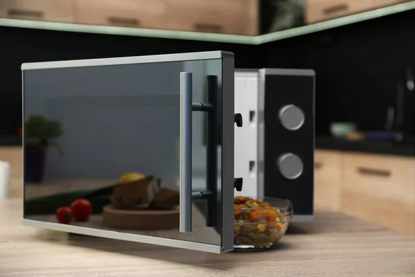 Open modern microwave oven on table in kitchen