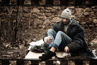 Şehir parkında karton üzerinde oturan zavallı evsiz adam