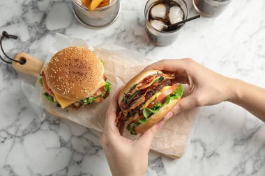 Servis masasında pastırma ile lezzetli burger tutan kadın, üst görünüm