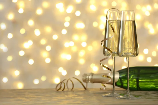 Brýle a láhev šampaňského na stůl proti rozmazaných světlech. Místo pro text — Stock fotografie