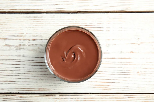 Стекло с вкусным шоколадным кремом на деревянном фоне, вид сверху — стоковое фото