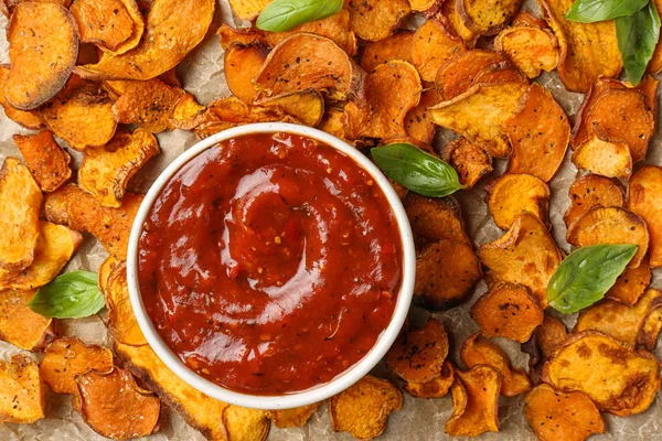 Zoete aardappel chips en kom saus op perkament, bovenaanzicht — Stockfoto