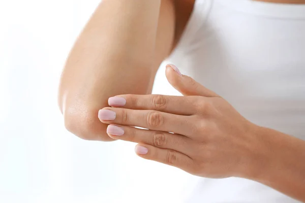 Mujer joven aplicando crema sobre fondo blanco, primer plano. Belleza y cuidado corporal — Foto de Stock