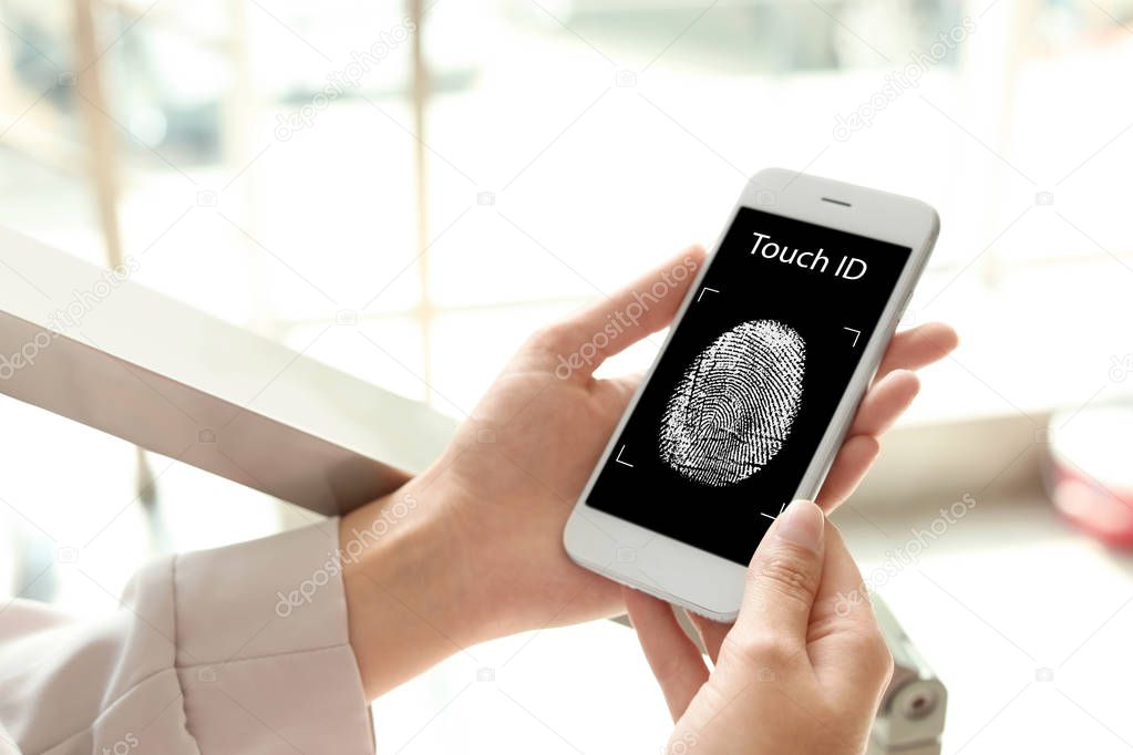 Woman holding mobile phone with fingerprint sensor indoors, closeup
