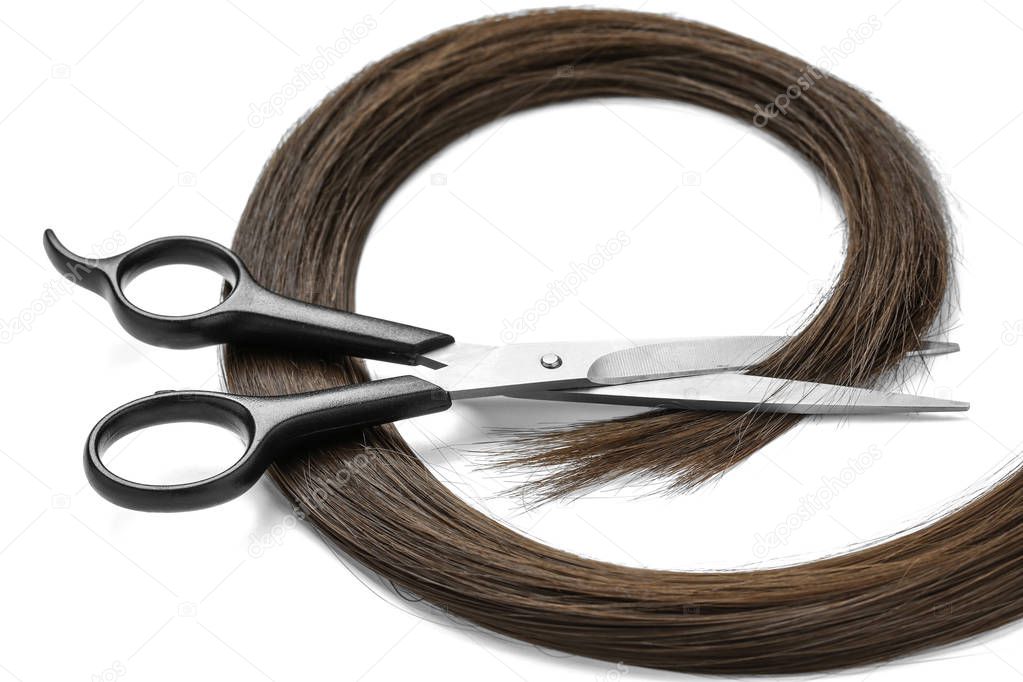 Brown hair and scissors on white background. Hairdresser service