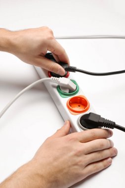 Adam beyaz arka planda uzatma kablosu içine güç fişi ekleme, çekim. Elektrikçi profesyonel ekipmanları