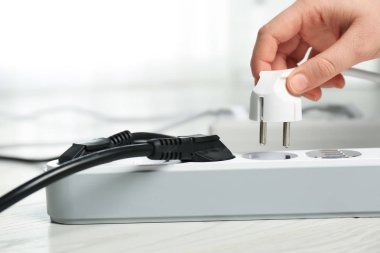 Kadın kapalı yerde uzatma kablosu içine güç fişi ekleme, metin için boşluk ile çekim. Elektrikçi profesyonel ekipmanları