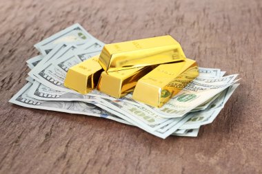 Masada parlak altın çubuklar ve dolar faturaları