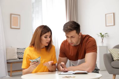 Üzgün çift oturma odasında para sayma
