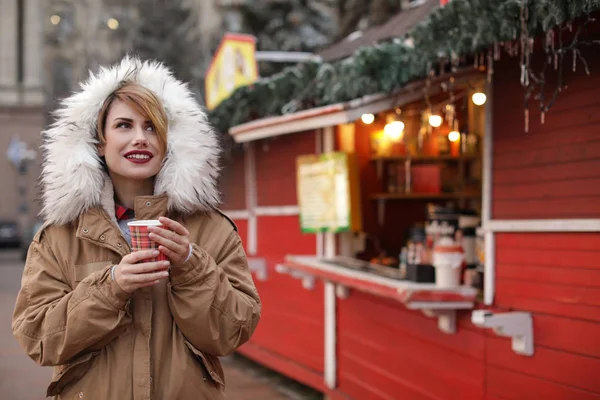 Жінка з чашкою глінтвейну на зимовому ярмарку. Простір для тексту — стокове фото