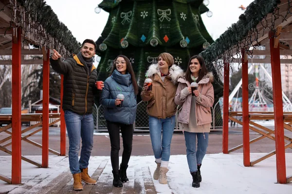 Friends with cups of mulled wine at winter fair — Stock Photo, Image