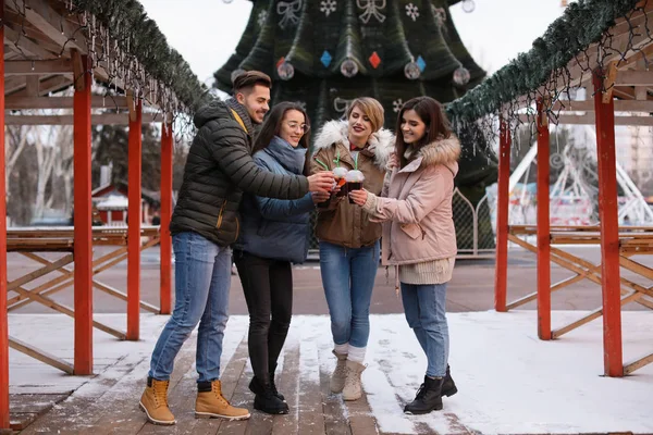 Friends with cups of mulled wine at winter fair — Stock Photo, Image