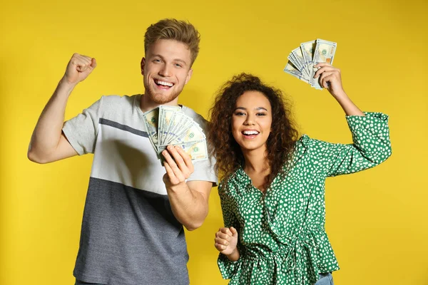 Junges Paar mit Geld auf farbigem Hintergrund — Stockfoto