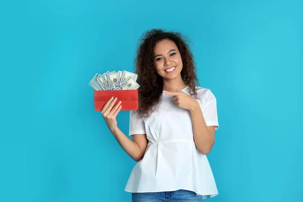 Afrikanisch-amerikanische Frau mit Geld im Portemonnaie auf farbigem Hintergrund — Stockfoto