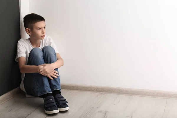 Расстроенный мальчик сидит на полу в помещении. Пространство для текста — стоковое фото