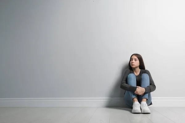 Menina adolescente perturbado sentado no chão perto da parede. Espaço para texto — Fotografia de Stock