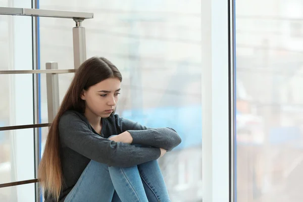 Aufgebrachte Teenager, die drinnen am Fenster sitzen. Raum für Text — Stockfoto