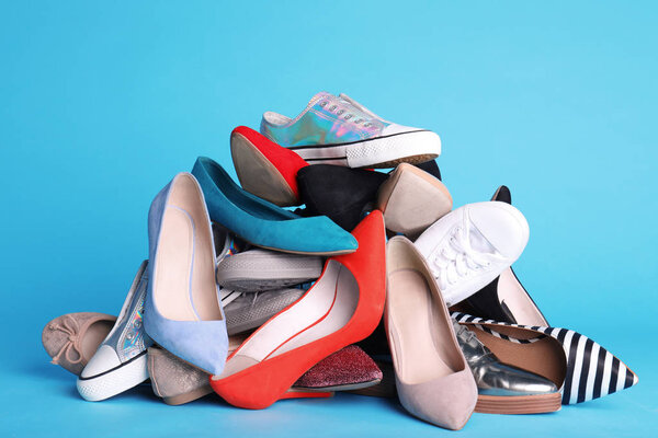 Heap of different shoes on color background
